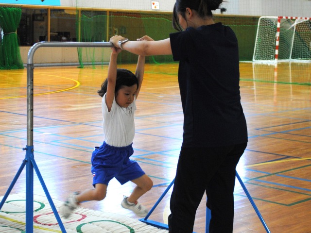 鉄棒にぶら下がる練習をする女の子