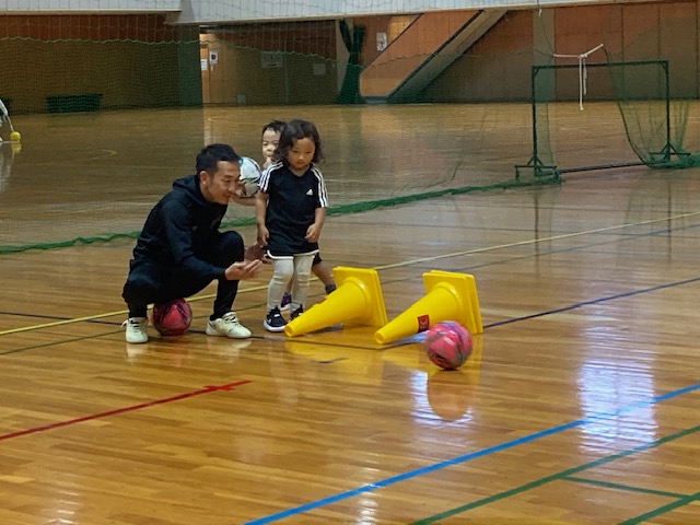 横になった２つの黄色いコーンを飛び越えてからボールを追いかけてゴールに走る生徒