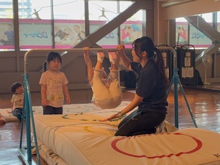 てつぼうに足をつけてぶら下がる練習をする年少の子供