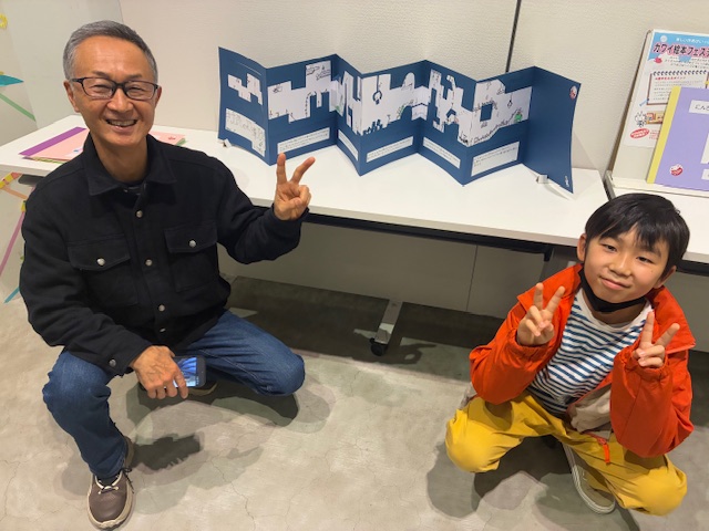 作品の前で、生徒と所長がピース