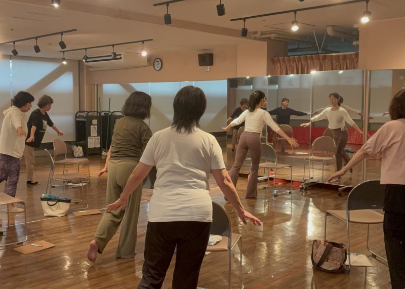 椅子から立って片足でバランス感覚を鍛えるストレッチをしています